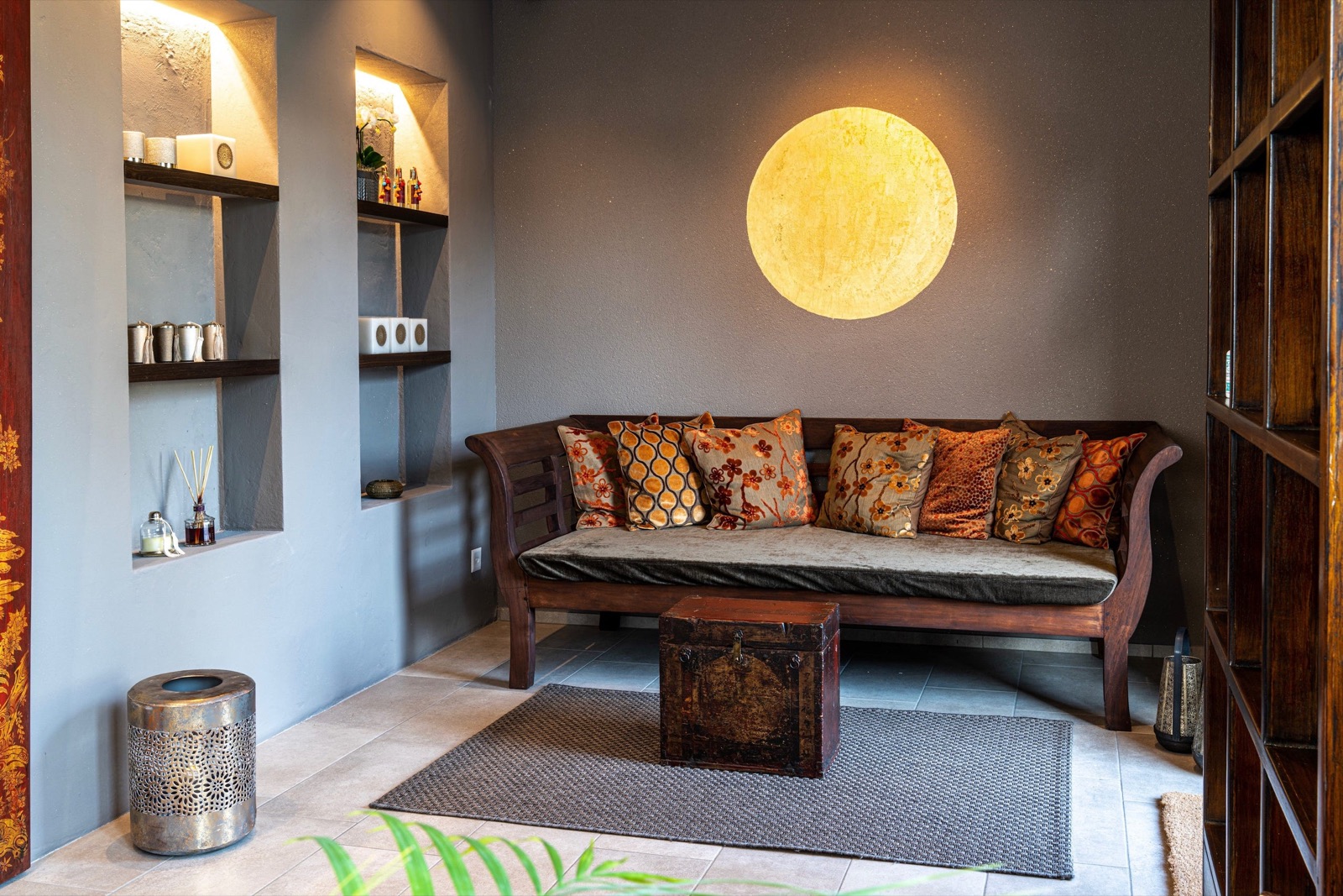 Lounge mit Holzsofa, orangen Kissen und leuchtendem Mond